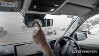 Driver adjusting the Rear View Camera touchscreen mirror inside a ute cab